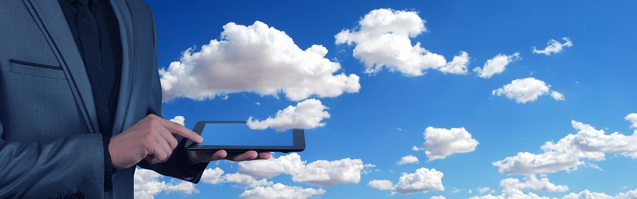 Businessman with tablet and clouds in background